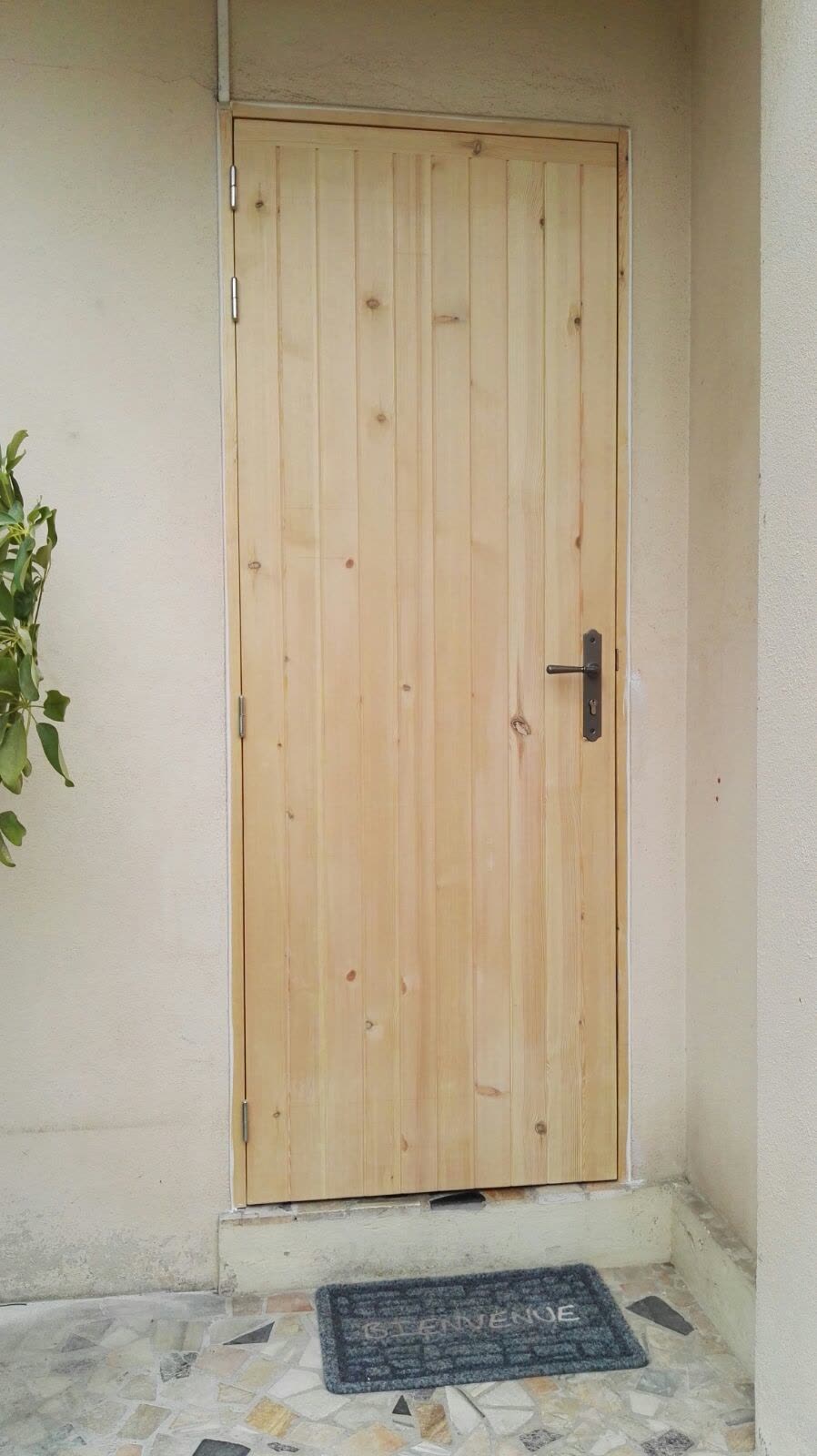 Porte en bois à panneaux installée dans une entrée